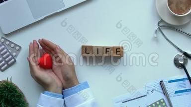 桌子上用木立方体做成的生活字，医生用手展示玩具<strong>心</strong>脏的俯视图